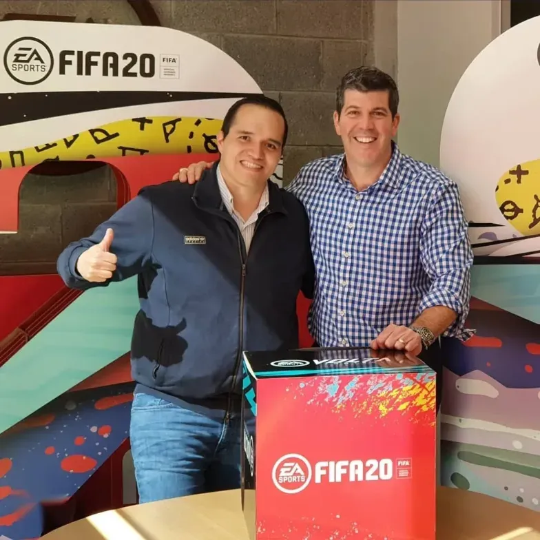 Dos personas en un evento del videojuego de Electronic Arts "Fifa 20", a la derecha Fernando Palomo con una mano en una caja que tiene el logo del videojuego