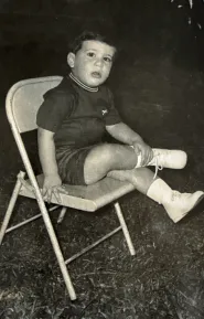 Fernando Palomo de niño, sentado en una silla plegable.