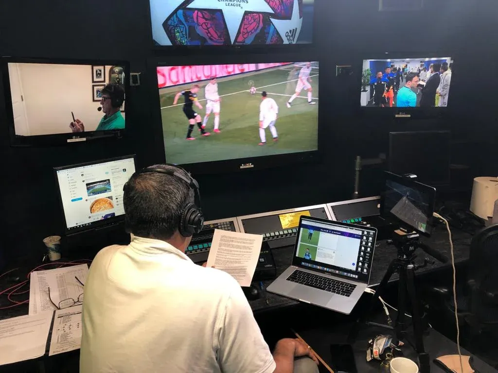 Fernando Palomo prepara una transmisión en la cabina, frente a monitores y con los auriculares puestos.