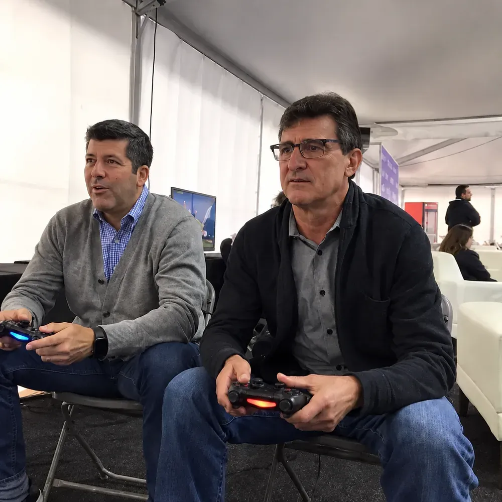 Fernando Palomo y Mario Kempes jugando un videojuego.